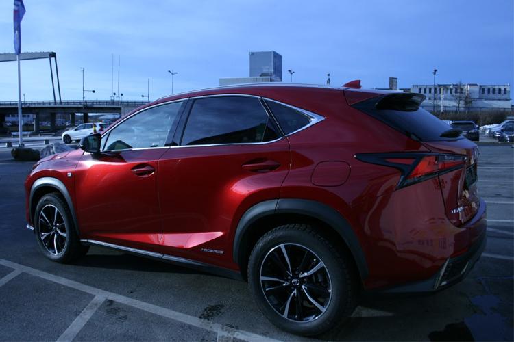 Rød SUV parkert på en parkeringsplass med bygninger i bakgrunnen.