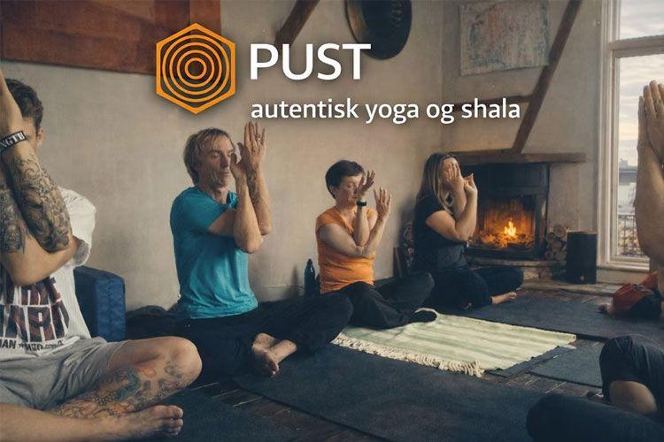 En gruppe mennesker praktiserer yoga i en koselig shala med peis og naturlig lys.