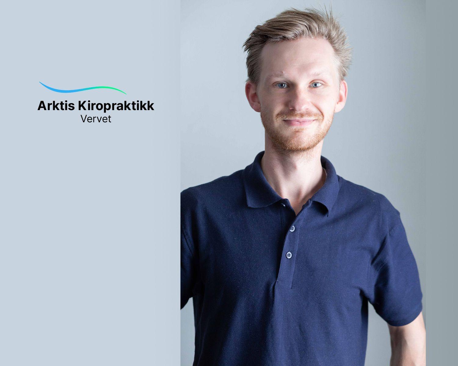 En smilende mann i blå polo skjorte står foran en lys bakgrunn med Arktis Kiropraktikk-logoen.