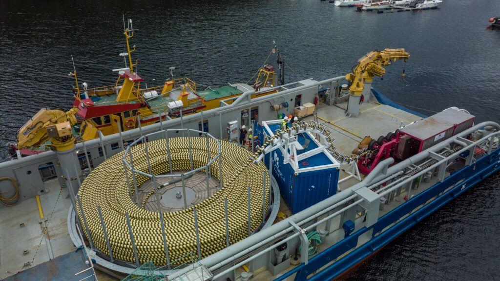 Fartøy med en stor rull av fiskenett og utstyr for fiske i en havn.