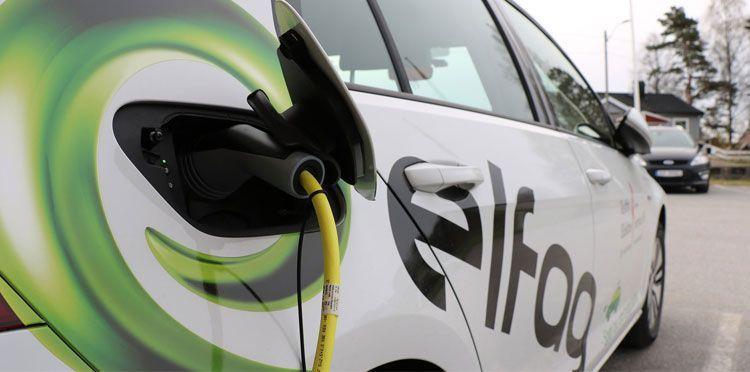 Ladekontakt på en elektrisk bil med en grønn logo og kabel til lading.