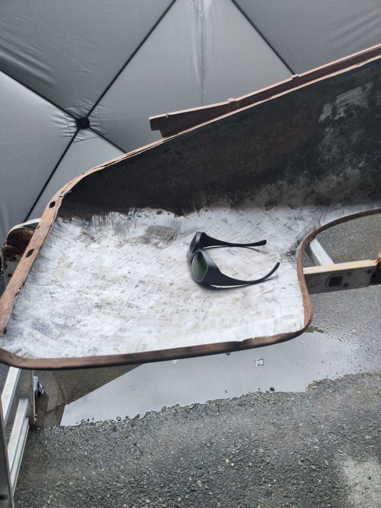 En rusten bildel med en solbrille på en hvit, isolert overflate i et telt.