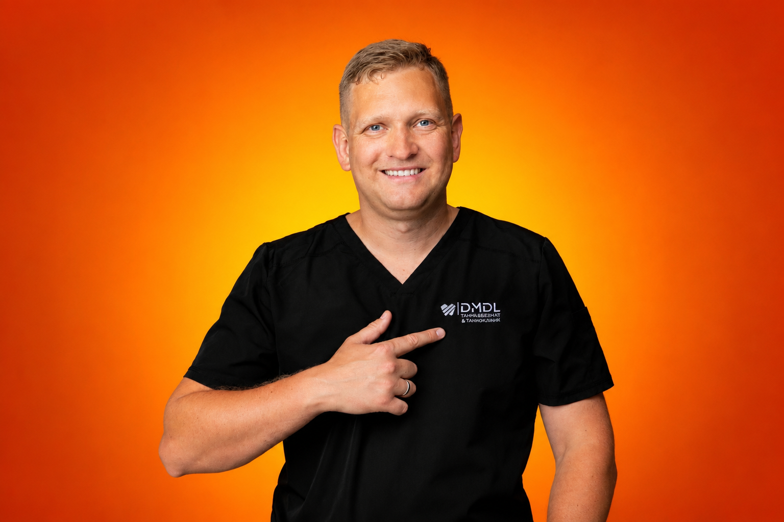 En smilende mann i svart legefrakk peker på logoen sin mot en oransje bakgrunn.