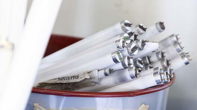 En beholder med flere hvite lysrør stablet oppå hverandre, med metallholdere synlige på endene.