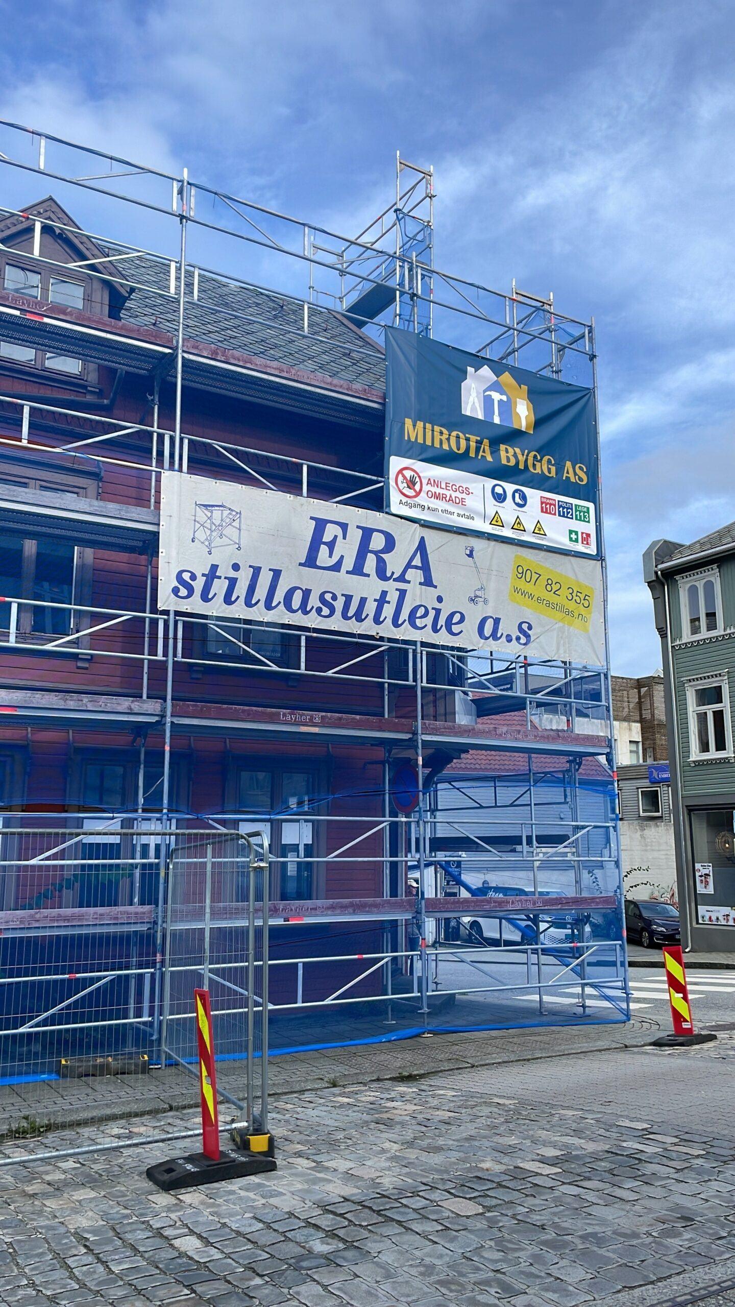 Bygning med stillas og reklameskilt for ERA stillasutleie a.s. under renovering i en bygate.