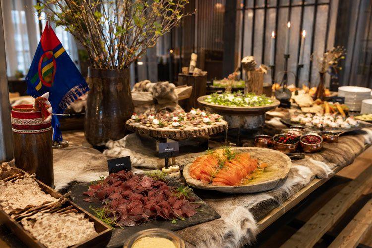 Et variert buffetbord med tradisjonell samisk mat, inkludert røkt laks, kjøttretter og friske grønnsaker.