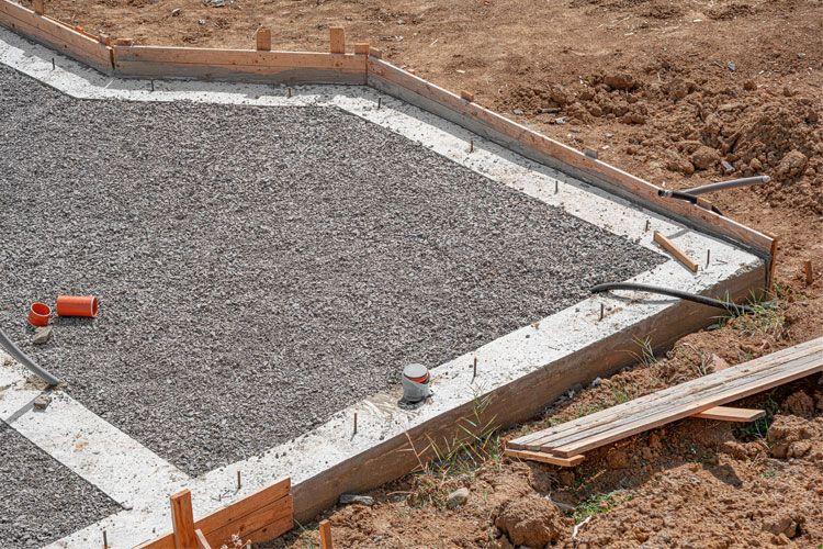Betongfundament med grus og forskaling på byggeplass, klar for videre konstruksjon.
