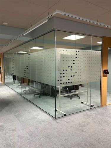 Moderne kontor med glassvegg og en kreativ romdelingsløsning med perforerte paneler.