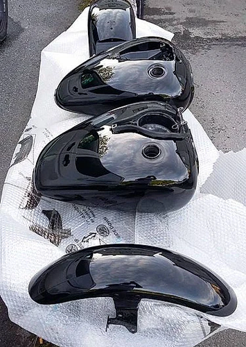 Fire svarte motorcykeltanker på hvitt beskyttelsesmateriale.