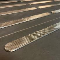 Nærbilde av metallplater med rutenettmønster, lagt på en flat overflate.