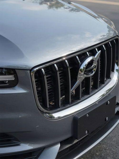 Nærbilde av en grå Volvo med karakteristisk grill og logo, parkert langs veien.