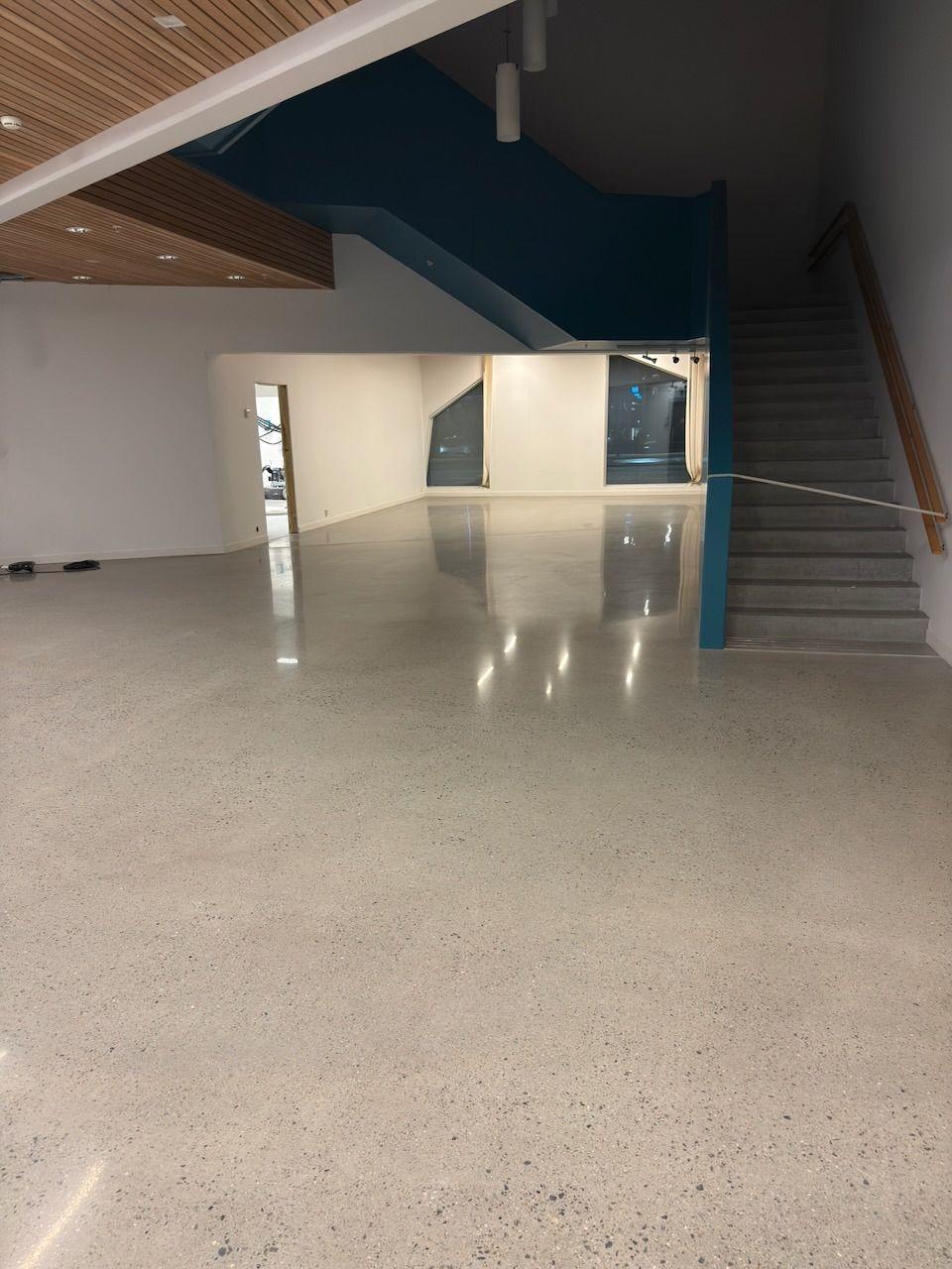 Moderne inngangsparti med polert betonggulv og en blå trapp i bakgrunnen.