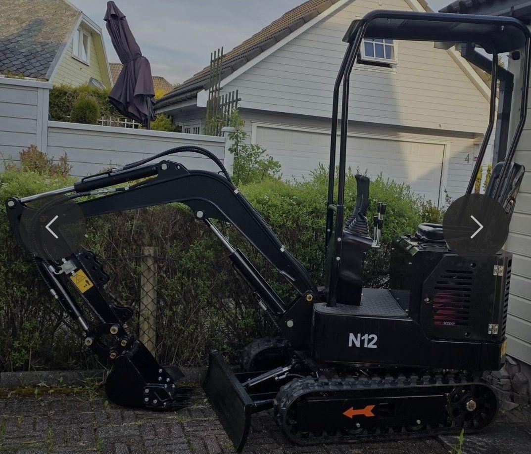 Gravemaskin parkert i hagen, med grønt buskas og hus i bakgrunnen.