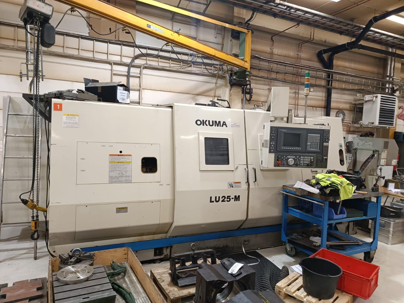 Bilde av en Okuma LU25-W CNC-maskin i en verkstedsetting med verktøy og materialer rundt.