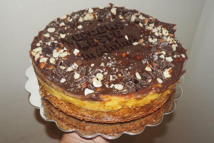 En sjokoladekake med nøtter og kremfyll, dekorert med sjokoladeflak og teksten "Gratulerer med dagen, mamma".