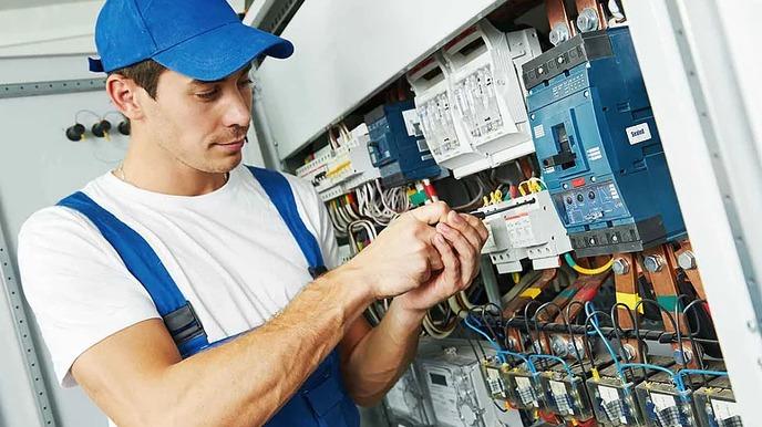 En elektriker som arbeider med elektriske ledninger i et skap.